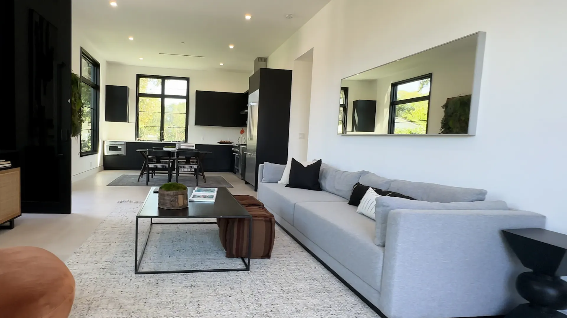 Open-plan living and kitchen after a whole-home renovation — black steel windows, white oak floors and a garden view