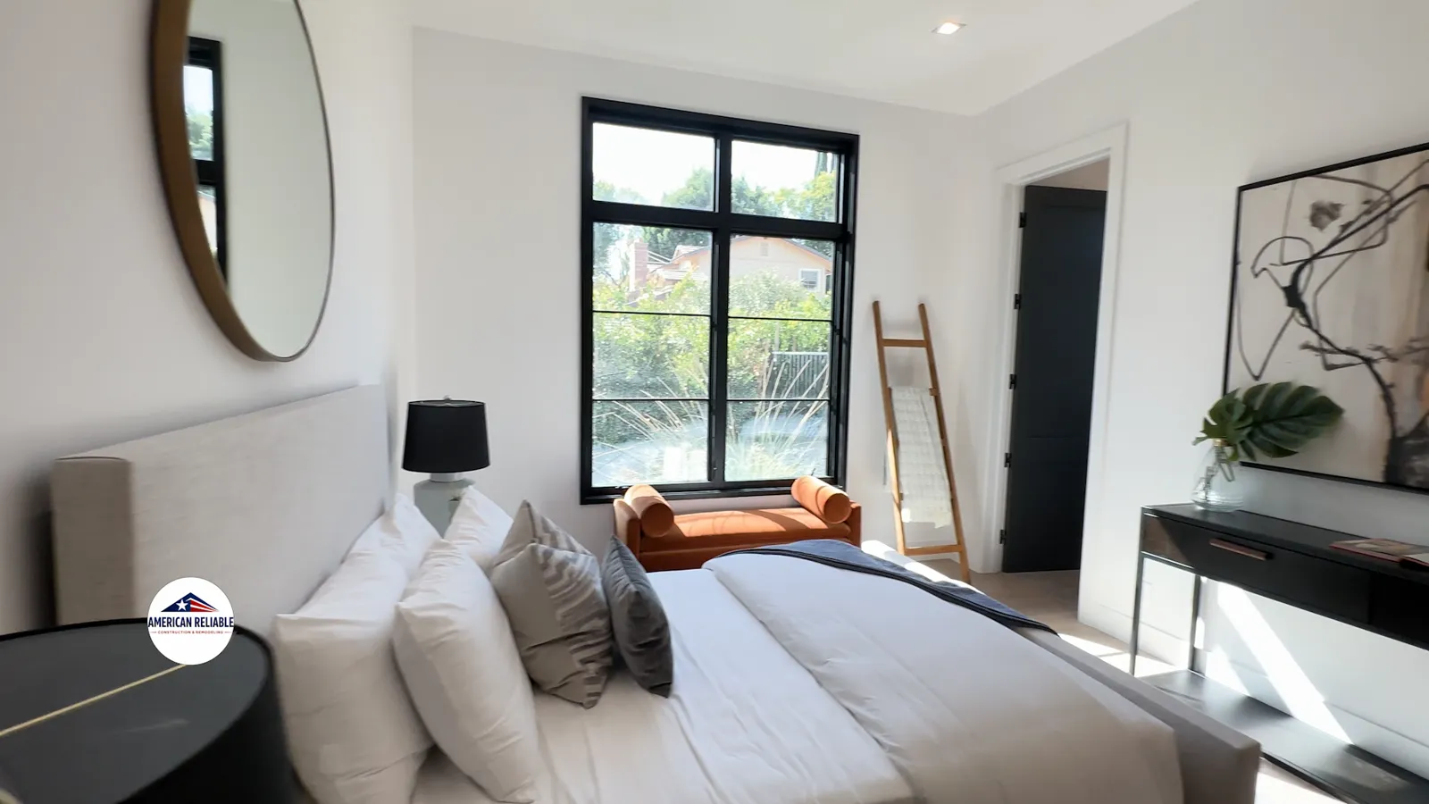 Bright bedroom with brass oval mirror and orange daybed